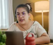 Transgender woman using laptop for conference call, working from home concept.