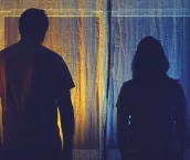 Silhouette of sad man and woman in a quarrel against the background of a night window. Divorce of husband and wife in the evening light of the home living room