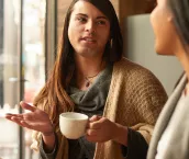 Cropped shot of an affectionate young gender fluid person having a discussion with their friend while having coffee in a cafe