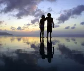 Children standing on beach at sunset