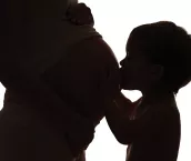 Happy family. Silhouette of toddler kissing belly of pregnant mother