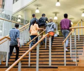 Male and female college students in casual clothing, on way to class, ascending staircase